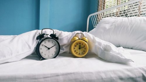 Alarm clocks on bed at home