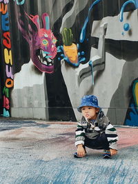 Full length of cute boy with graffiti on wall