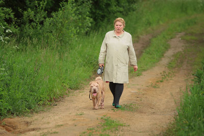 Full length of woman walking with dog on trail