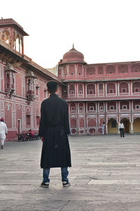 Rear view of man walking in front of historical building