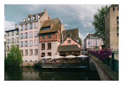 Buildings by river against sky