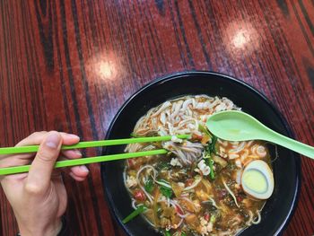 Close-up of hand holding bowl of soup