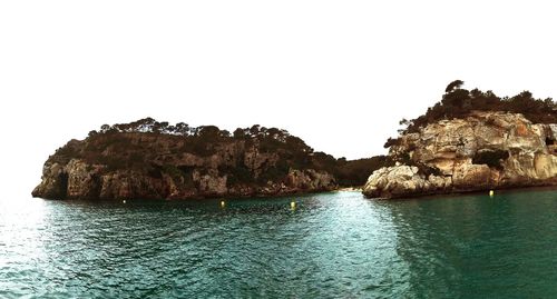 Rock formation by sea against clear sky