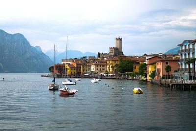 Sailboats in sea against buildings in city