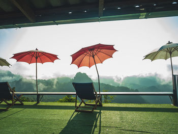 Parasols and chairs against sky during rainy season