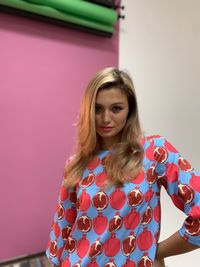 Portrait of woman standing against pink wall