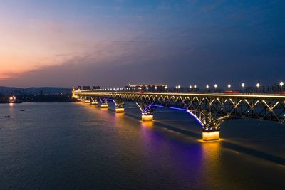 Illuminated bridge over river at night