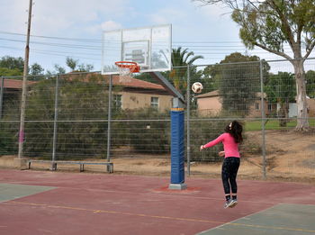 Man playing basketball hoop against sky