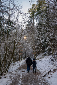 Rear view of women walking on snow covered tree