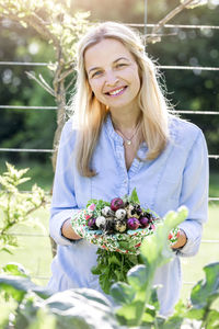 Portrait of mid adult woman holding radishes at farm