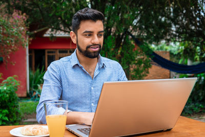 Young man using laptop at cafe