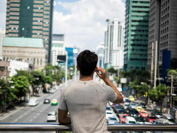 Rear view of woman using mobile phone on road in city