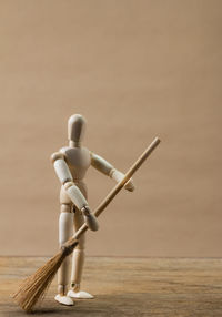 Close-up of figurine cleaning table with broom