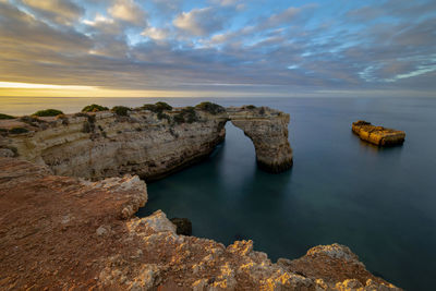 Rocks in sea against sky during sunset