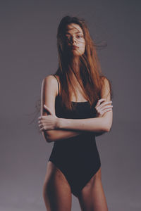 Portrait of young woman standing against wall