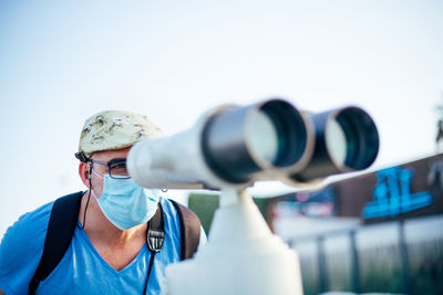 Portrait of man with face mask looking through binoculars