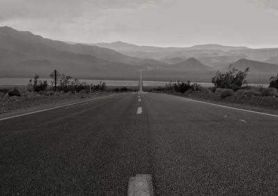 Road leading towards mountains against sky