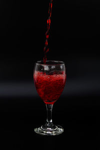 Close-up of red wineglass against black background