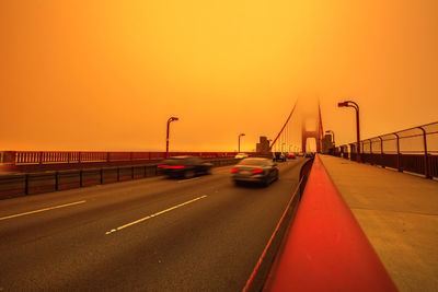 Vehicles on road against orange sky