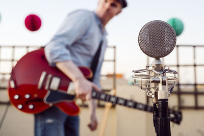 Man holding guitar standing on terrace