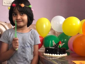 Girl of girl holding knife while sitting by cake on table