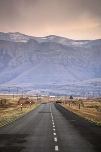 Road by mountains against sky