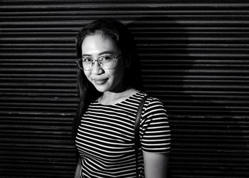 Portrait of smiling mid adult woman standing against wall