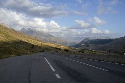 Road leading towards mountains against sky