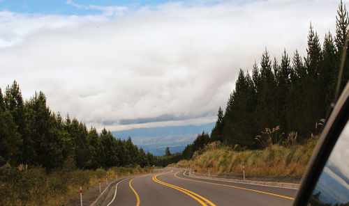 Road by trees against sky