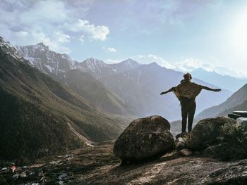 Man standing on rock by mountain against sky