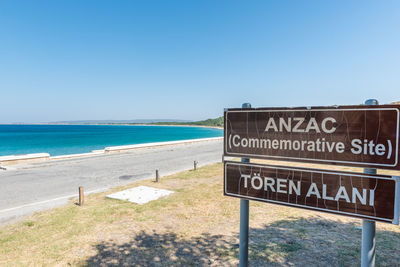 Information sign on beach against clear sky