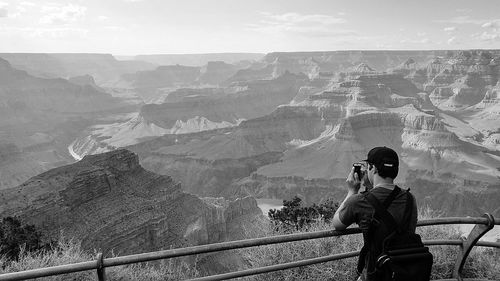 Rear view of man standing by railing at observation point against mountains