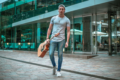 Full length portrait of young man walking on street in city