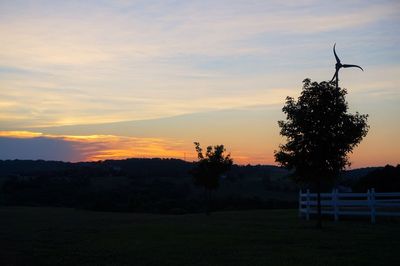 Silhouette trees on field against sky at sunset