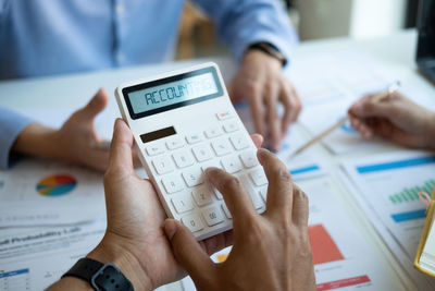 Midsection of man using calculator