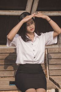 Full length of beautiful woman standing against wooden wall