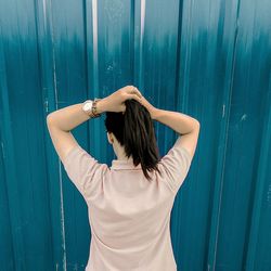 Rear view of young woman standing against wall