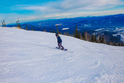 Rear view of man with snowboard standing on snow covered land