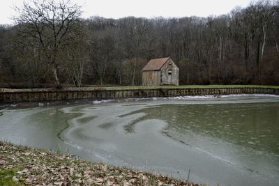 House by lake against sky