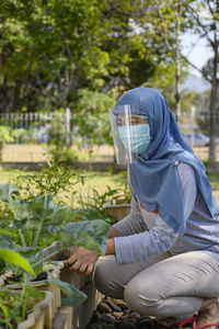A hijab woman is wearing masker and face shield while gardening in covid 19 pandemic situation