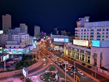 High angle view of illuminated street amidst buildings in city at night