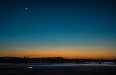 Scenic view of river against clear sky at sunset