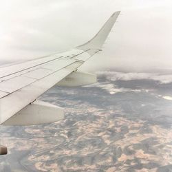 Cropped image of airplane flying over clouds