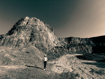 Rear view of man standing on mountain against sky