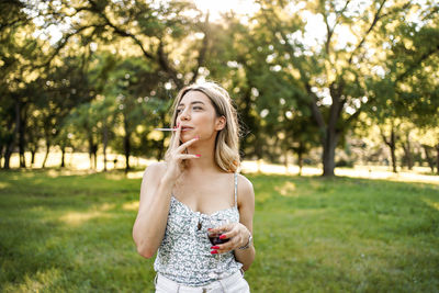 Portrait of young woman standing against trees