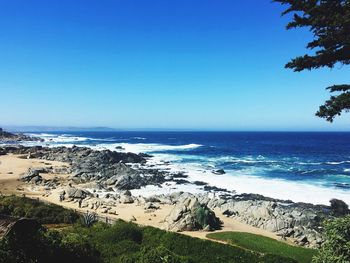 Scenic view of beach against clear blue sky