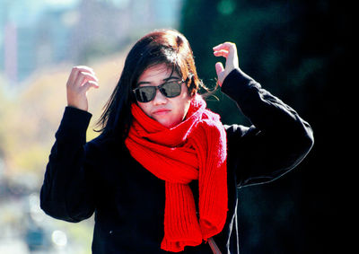 Portrait of young woman with arms raised in winter