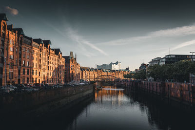 Bridge over river by buildings against sky in city