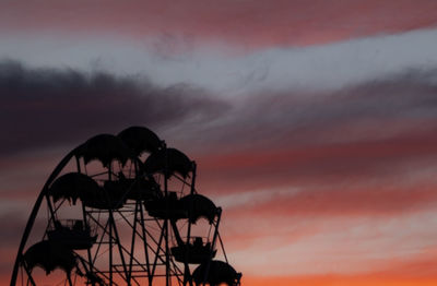 Low angle view of silhouette cranes against orange sky