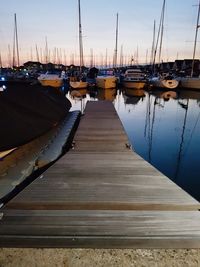 Sailboats moored at harbor against sky